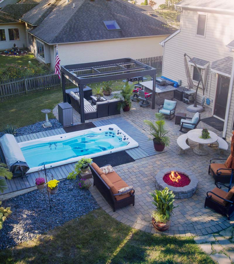 Aerial view of a cozy backyard with swim spa, outdoor fire pit, and plenty of seating