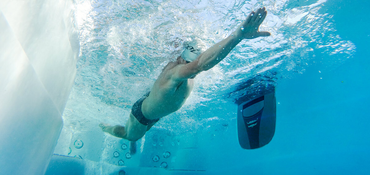Underwater view of someone swimming in a swim spa.